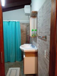 uma casa de banho com um lavatório e uma cortina de chuveiro azul em La Gitana - Casa en La Paloma em La Paloma