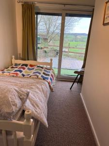 a bedroom with a bed and a large window at Otter Holt, beautiful East Devon in Tipton Saint John