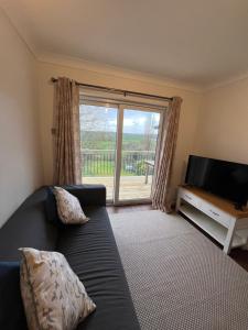 a living room with a couch and a large window at Otter Holt, beautiful East Devon in Tipton Saint John