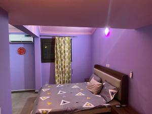 - une chambre violette dotée d'un lit avec un mur violet dans l'établissement THE LANDING LODGE-ABIDJAN, à Abidjan