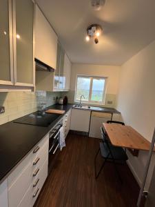 a kitchen with white cabinets and a wooden table at Otter Holt, beautiful East Devon in Tipton Saint John