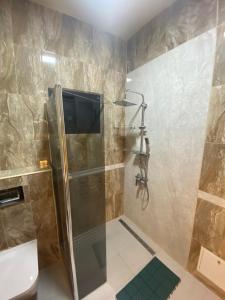 La salle de bains est pourvue d'une douche et d'une télévision murale. dans l'établissement THE LANDING LODGE-ABIDJAN, à Abidjan
