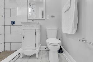 a white bathroom with a toilet and a sink at Fairmount Oasis 1BR Haven in Philadelphia