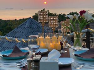 a table with plates and wine glasses and flowers on it at The Happinezz Hills Hotel in Karimunjawa