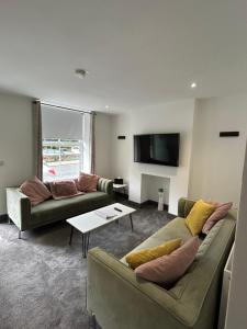 a living room with two couches and a tv at Cottage in Holmfirth Centre in Holmfirth