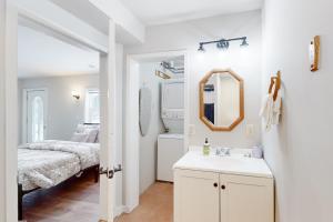een witte badkamer met een wastafel en een bed bij The Pup House in Manitowish Waters