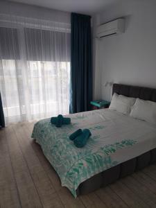 a bedroom with a bed with two green slippers on it at Astoria Apartament vedere la mare in Mamaia Sat/Năvodari