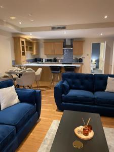 a living room with blue couches and a kitchen at Modern 2 BDR Flat in Nottingham City Centre with FREE Parking in Nottingham