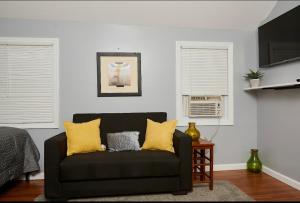 uma sala de estar com um sofá preto com almofadas amarelas em La Kaí em Saint Albans