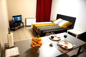 Charmant studio centre ville في لو بوي: غرفة مع سرير وطاولة مع كؤوس للنبيذ
