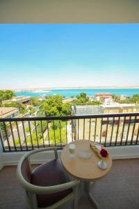 een tafel en stoel op een balkon met uitzicht op de oceaan bij Salvatore Room With Breakfast-Sea View in Suez