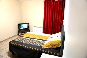 Charmant studio centre ville في لو بوي: غرفة نوم بسرير وستارة حمراء