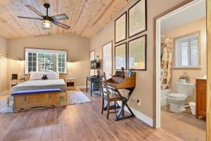 a bedroom with a bed and a desk and a bathroom at Whispering Woods Big Bear~ Central Resort Cottage~ in Big Bear Lake