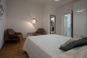 ein weißes Schlafzimmer mit einem Bett und zwei Stühlen in der Unterkunft Adam 2 in Stobreč
