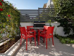 ein Tisch und vier rote Stühle auf einer Terrasse in der Unterkunft Adam 2 in Stobreč