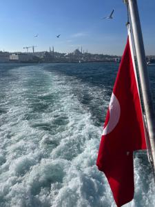 a boat with a red flag on the water at Lux sea view willas in Istanbul
