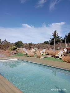 a swimming pool with two lawn chairs and a table at Cabañas Toconao in Algarrobo