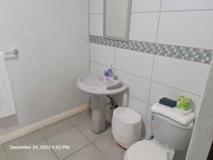 Baño blanco con lavabo y aseo en Sandcastle Beach Apartments, en Palm-Eagle Beach