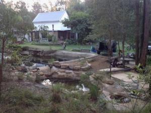 a yard with a pond and a house and a house at Yamba Hinterland bush retreat - Vintage bus stay in Dilkoon