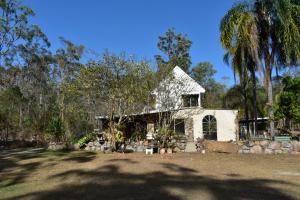 una vecchia casa bianca con degli alberi davanti di Yamba Hinterland bush retreat - Vintage bus stay a Dilkoon