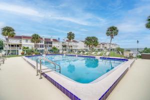 a swimming pool at a resort with palm trees and condos at Riverfront Townhome in Titusville Community Pool in Titusville