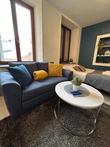 a living room with a blue couch and a table at Studio de 30m² hypercentre très calme in Montbéliard