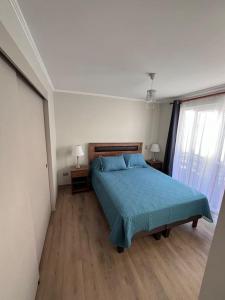 a bedroom with a bed with a blue bedspread at Cómoda casa nueva 3 D 2 B in La Serena