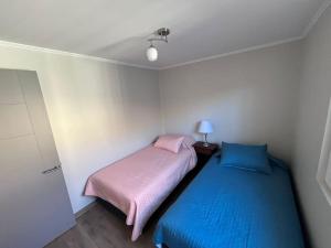 Dormitorio pequeño con 2 camas y lámpara en Cómoda casa nueva 3 D 2 B, en La Serena