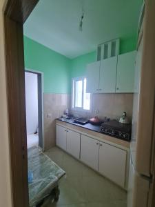 uma cozinha com paredes verdes e armários brancos em appart near the Airport and beach Tanger gzenaya 2 rooms em Tânger