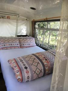 a bed in the middle of a room with a window at Yamba Hinterland bush retreat - Vintage bus stay in Dilkoon