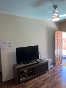 uma sala de estar com uma televisão de ecrã plano num centro de entretenimento em Casa com piscina para temporada - Unamar, Cabo Frio - RJ em Cabo Frio