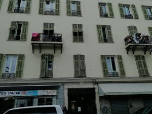 - un grand bâtiment blanc avec des fenêtres et des balcons dans l'établissement Le PETIT JEAN, à Nice