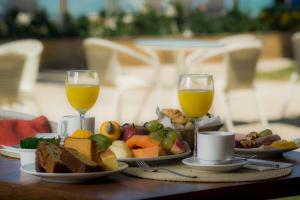 a table with two glasses of orange juice and food at Jatiuca Hotel & Resort in Maceió