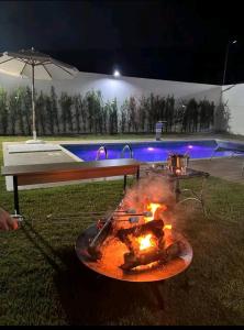 a fire pit in the grass next to a pool at night at Casa do Ninho 1 in Quadra
