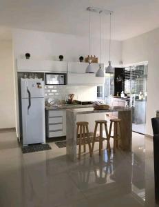 Casa do Ninho 1 في Quadra: مطبخ مع ثلاجة بيضاء وطاولة مع كراسي