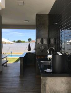 uma cozinha com um lavatório e vista para uma piscina em Casa do Ninho 1 em Quadra