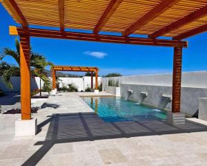 a swimming pool under a wooden pergola at Pool Condo, just a few steps from the beach -north in Los Barriles
