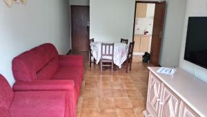 sala de estar con sofá rojo y mesa en Apartamento Guarapari Praia Castanheiras, en Guarapari