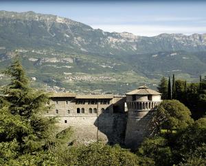 a building on a hill with mountains in the background at Hotel Sant'Ilario in Rovereto