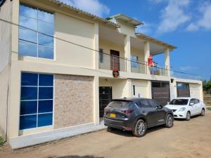 two cars parked in front of a house at Cabana Acunas House in Santa Marta