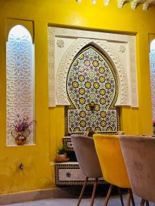 a yellow wall with two chairs and aificantificantificantificantificantificantificantificant at DAR AL NOUR in Marrakesh