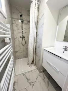 ein weißes Bad mit einer Dusche und einem Waschbecken in der Unterkunft Cocon cosy entre Paris et Disney - Le Camélia in Champigny-sur-Marne