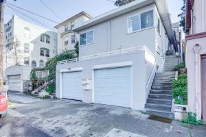 ein weißes Haus mit zwei Garagentüren und Treppen in der Unterkunft Oakland Apartment with Shared Hidden Backyard Oasis! in Oakland