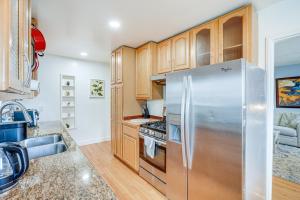 a kitchen with wooden cabinets and a stainless steel refrigerator at Oakland Apartment with Shared Hidden Backyard Oasis! in Oakland