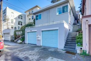 a white house with two garage doors and stairs at Pet-Friendly Oakland Apt with Hot Tub and Fire Pit! in Oakland