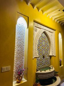 a bathroom with a yellow wall with a mosaic sink at DAR AL NOUR in Marrakesh