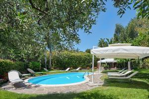 een zwembad met een parasol en stoelen en een tafel en een parasol bij Casa Vacanze Nel Giardino di Renzo in Imperia