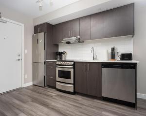 a kitchen with wooden cabinets and stainless steel appliances at Hendrix Luxury Apartments by Corporate Stays in Edmonton