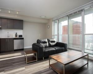 a living room with a black leather couch and a table at Hendrix Luxury Apartments by Corporate Stays in Edmonton