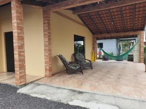 un patio extérieur avec deux chaises et un hamac dans l'établissement Casa de Praia- Village Dunnas- Bal. Gaivota-SC, à Balneário Gaivotas